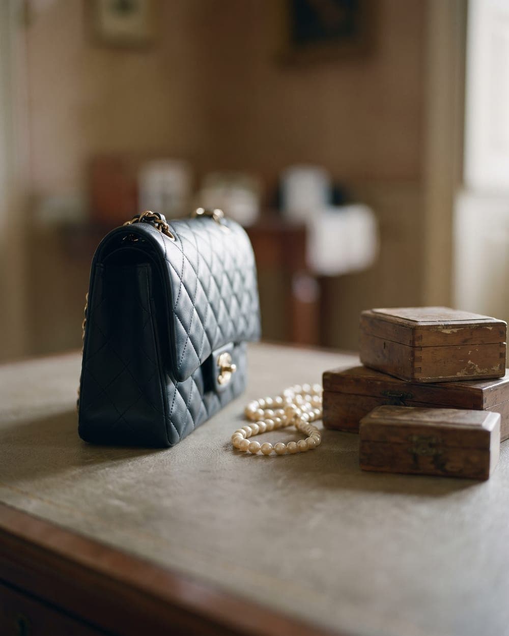 Elegante Ledertasche mit Perlenkette und gestapelten Vintage-Schatullen